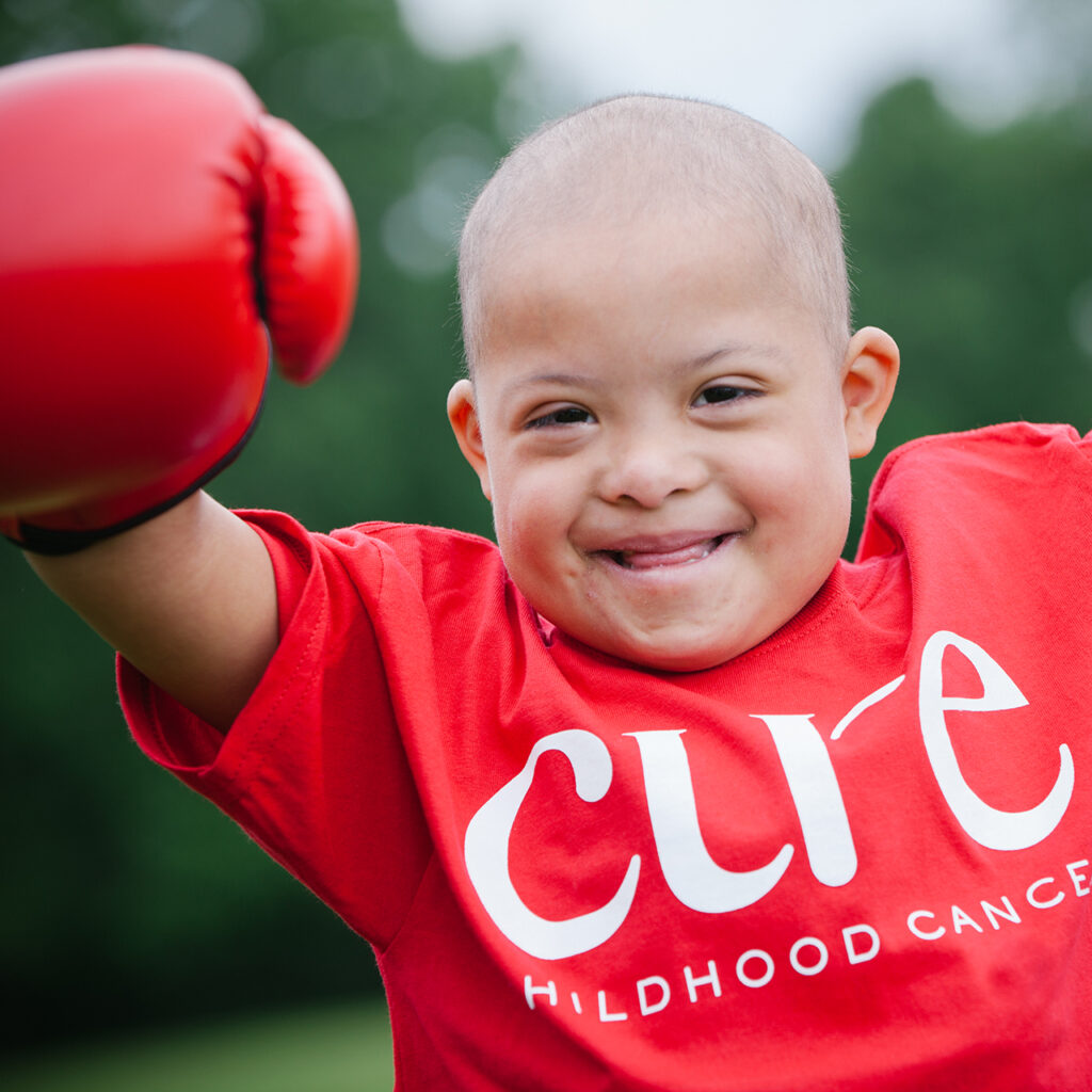 CURE Flags smiling child punching the right side of the image wearing boxing gloves