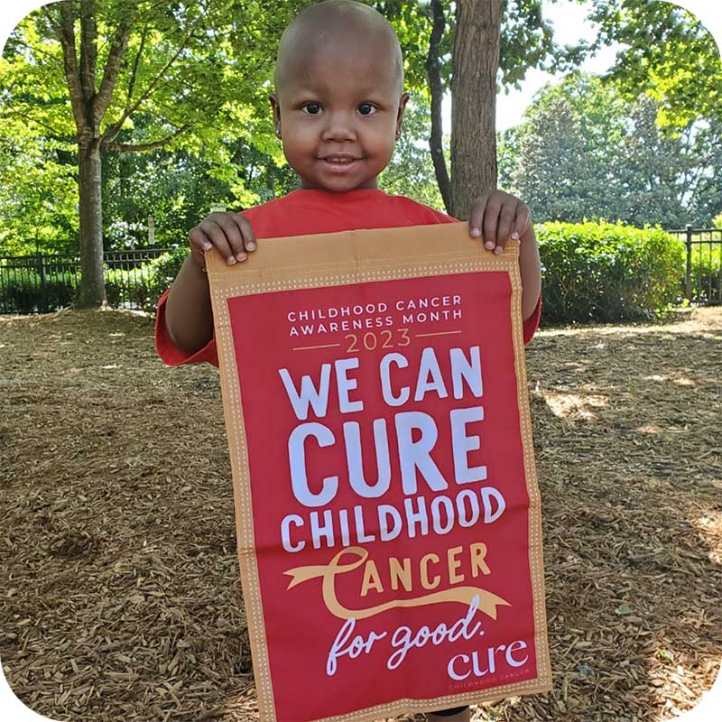 Child holding red "We Can Cure Childhood Cancer for Every Child" garden flag