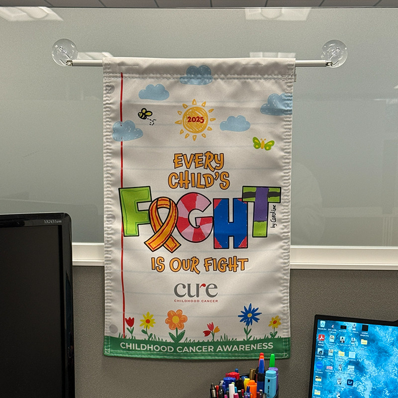 CURE pediatric cancer flag positioned inside a healthcare or office space