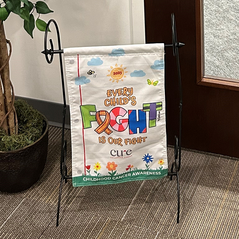 Awareness flag set up indoors on a metal stand near office plants